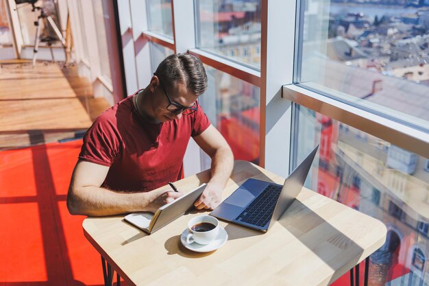 Foto desenvolvedor de software inteligente sentado na área de trabalho em um espaço de coworking com laptop e criando uma ideia de publicação usando netbook para mensagens e redes durante o trabalho freelance