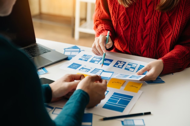 Desenvolvedor de UX e designer de UI brainstorming sobre interface de aplicativo móvel wireframe design com cliente breif e código de cor no escritório