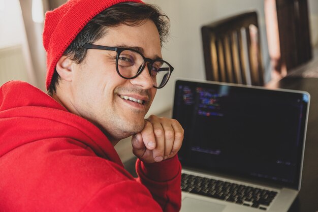 Foto desenvolvedor jovem com roupas vermelhas, trabalhando com o computador do escritório em casa