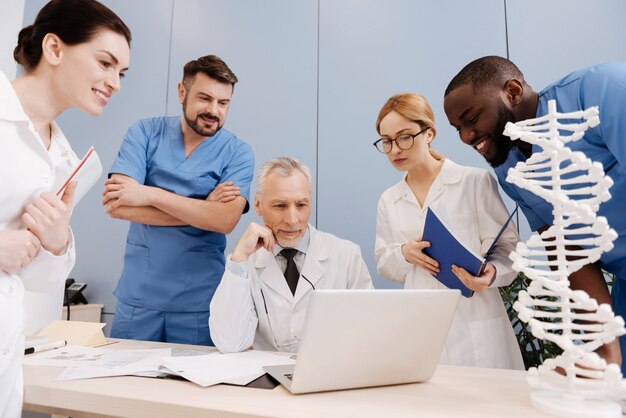 Desenvolver curiosidade intelectual. Médico experiente e qualificado trabalhando e conduzindo a palestra na faculdade enquanto consultava aprendizes e usava gadget