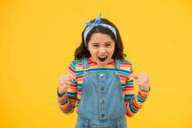 Desenvolvimento infantil e problemas na adolescência. fundo amarelo de criança pequena. criança gritando à moda antiga. beleza e moda. cabelo comprido de menina pequena. período de transição da infância. garota retrô expressar raiva.