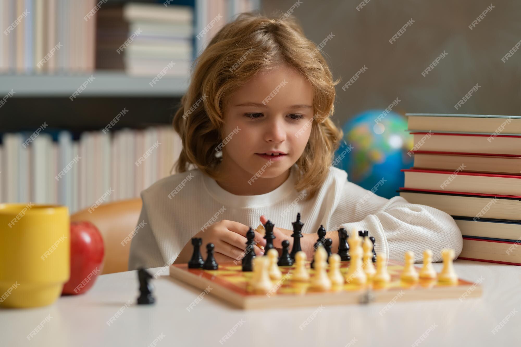 Escola de xadrez xadrez infantil concentrado jogo infantil inteligente  xadrez na biblioteca perto das estantes conceito educacional menino  pensando em xadrez o conceito de aprender e crescer crianças