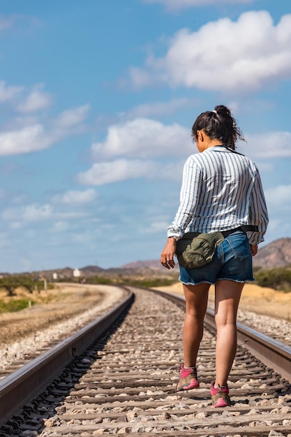 Foto desert wanderer mujer latina abrazando el sol en las vías del tren
