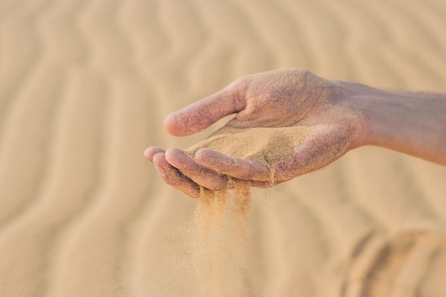 Deserto, areia sopra pelos dedos da mão de um homem