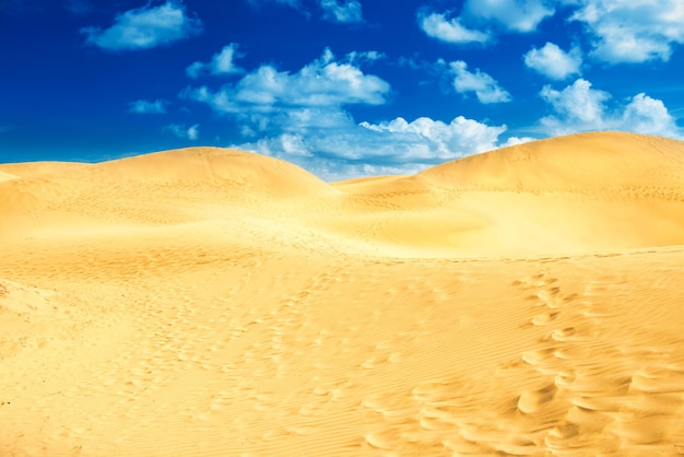 Deserto com dunas de areia e nuvens no céu azul. paisagem da reserva natural dunas de maspalomas. gran canária, espanha