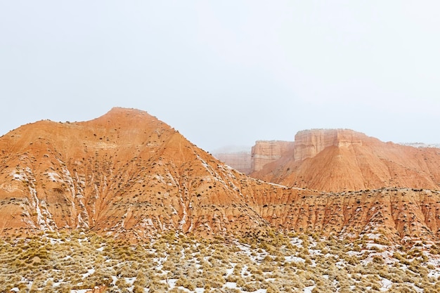 Deserto com montanhas marrons parcialmente cobertas de neve.