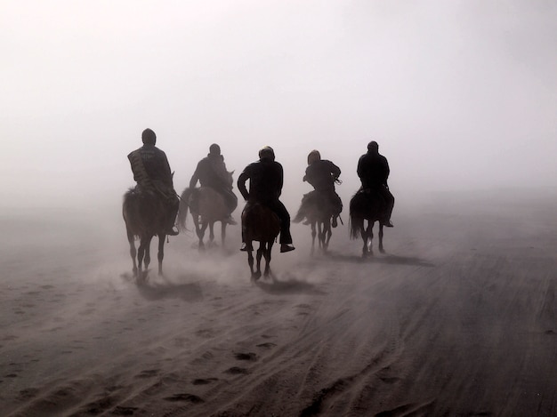 Foto deserto de bromo e cavaleiros durante a tempestade de areia em bromo