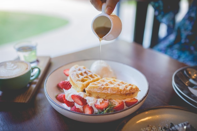 Foto deserto de panqueca de waffle com sorvete de baunilha, morango fresco e calda de mel