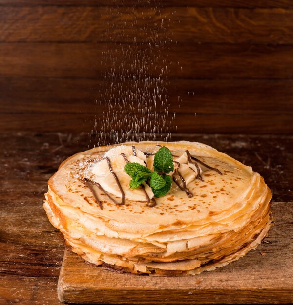 Deserto isolado - pilha de panqueca com banana em uma mesa de madeira