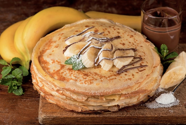 Deserto isolado - pilha de panqueca com pasta de chocolate e banana em uma mesa de madeira