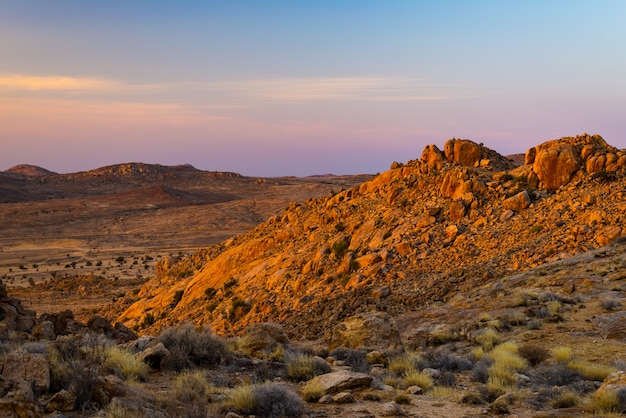 Deserto rochoso ao entardecer, pôr do sol colorido sobre o deserto do Namibe, Namíbia, África