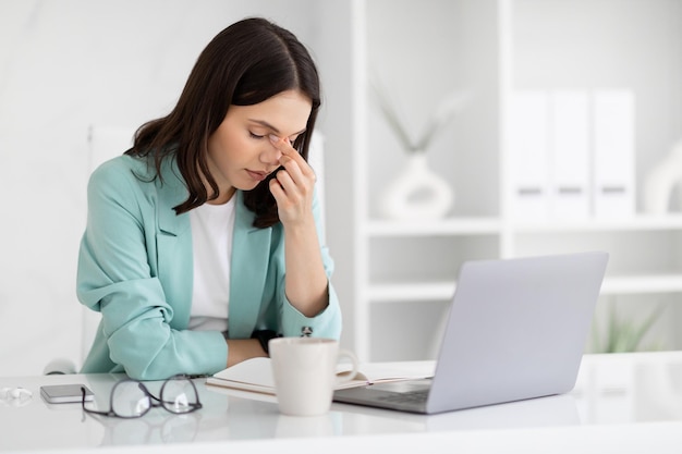 Desesperada y cansada, una mujer de negocios europea con una computadora portátil sufre de problemas laborales.