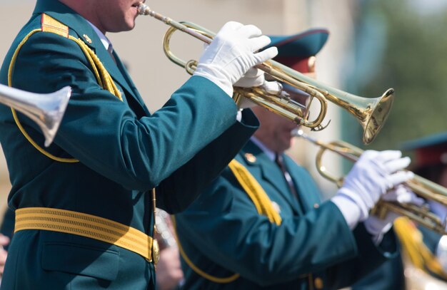 Un desfile de instrumentos de viento hombres en trajes verdes tocando la trompeta