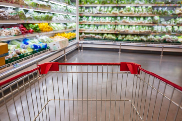 Desfocado desfoque um carrinho de compras colocado no chão de comida vegetal em um supermercado