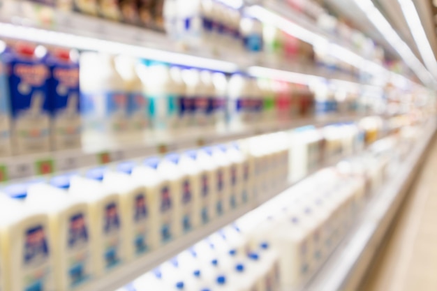 desfoque as prateleiras da geladeira da mercearia do supermercado com garrafas de leite fresco e produtos lácteos