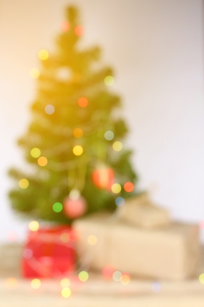 Desfoque de fundo, celebração de luz na árvore de Natal com caixa de presente na sala de estar