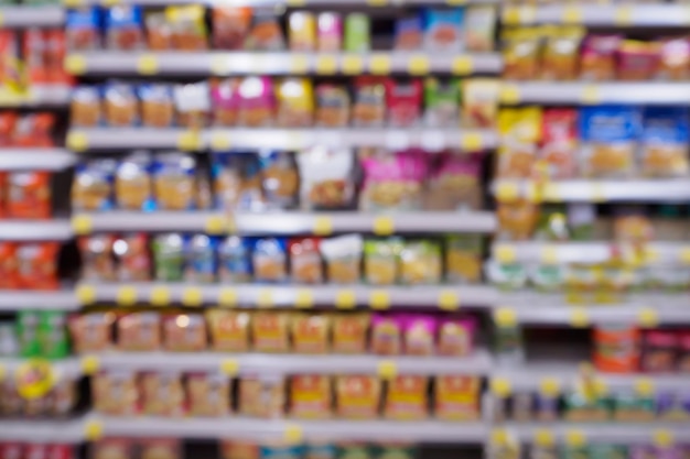 Foto desfoque o supermercado com variedade de produtos de chips de lanches de fast food nas prateleiras no fundo da loja