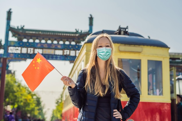 Desfrutando de férias na China jovem em máscara médica com bandeira nacional chinesa no fundo