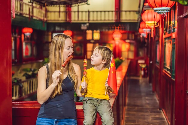 Desfrutando de férias na china turistas felizes mãe e filho com uma bandeira chinesa e com tradicional