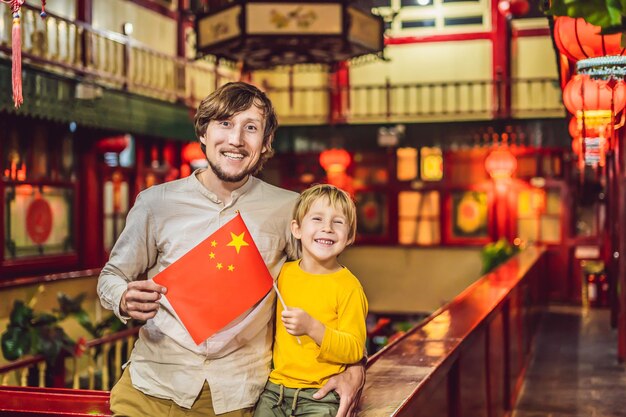 Desfrutando de férias na china turistas felizes pai e filho com uma bandeira chinesa em um fundo chinês