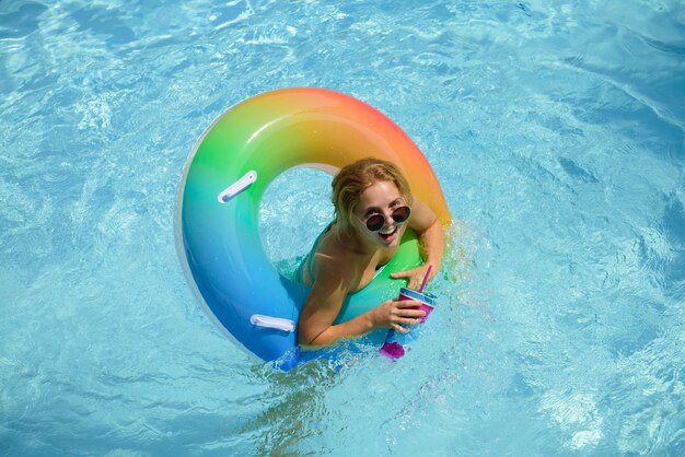 Desfrutando de mulher bronzeada em traje de banho no anel de natação na piscina festa de piscina de férias de verão