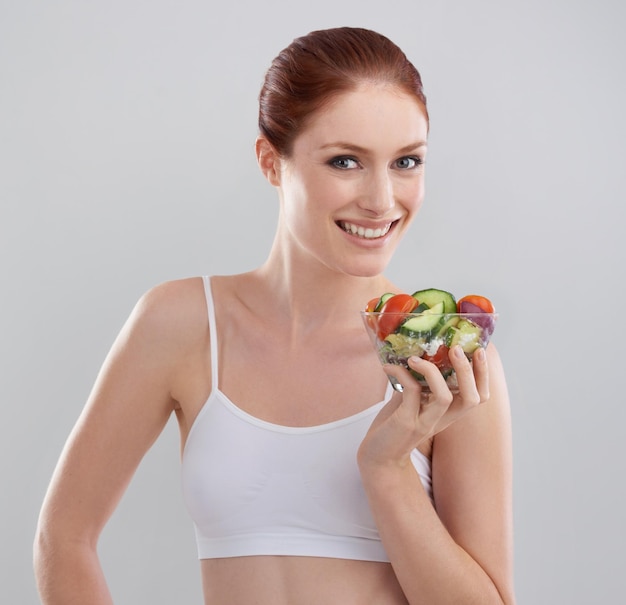 Desfrutando de sua dieta Foto recortada de uma jovem esportiva no estúdio com uma salada