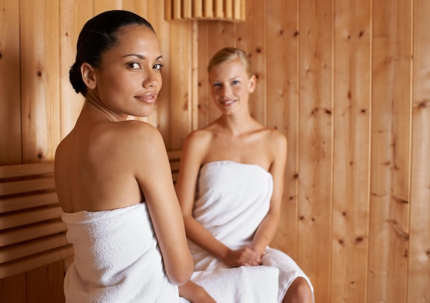 Desfrutando de um dia de spa com um amigo Duas jovens na sauna juntas