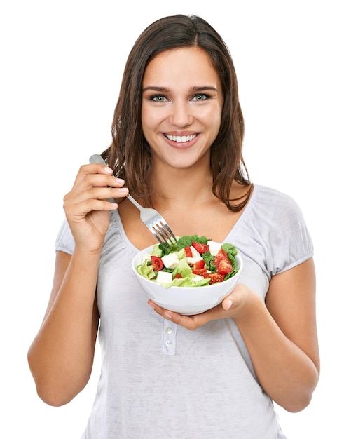 Desfrutando de um lanche saudável Uma jovem desfrutando de uma salada fresca isolada em branco