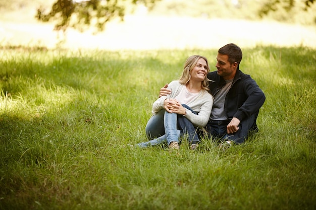 Desfrutando de um momento longe de tudo Foto de um jovem casal amoroso sentado na grama em um parque