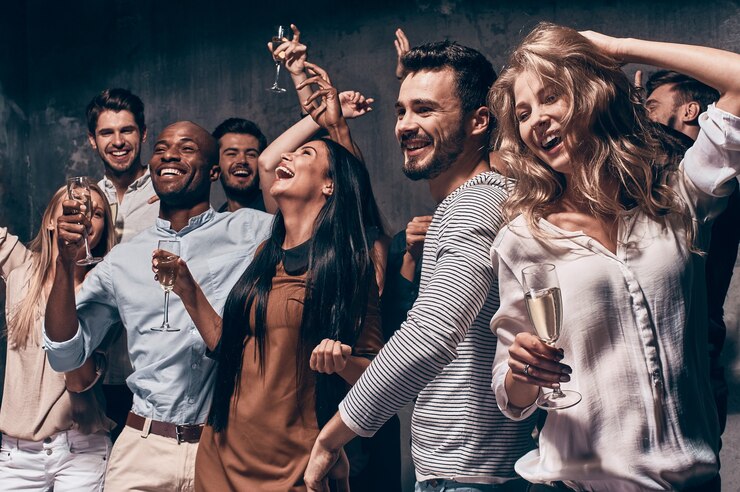 Foto desfrutando de uma festa incrível. grupo de jovens lindos dançando com taças de champanhe e parecendo felizes
