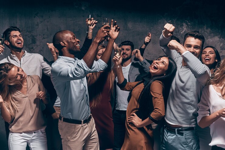 Foto desfrutando de uma festa incrível. grupo de jovens lindos dançando com taças de champanhe e parecendo felizes
