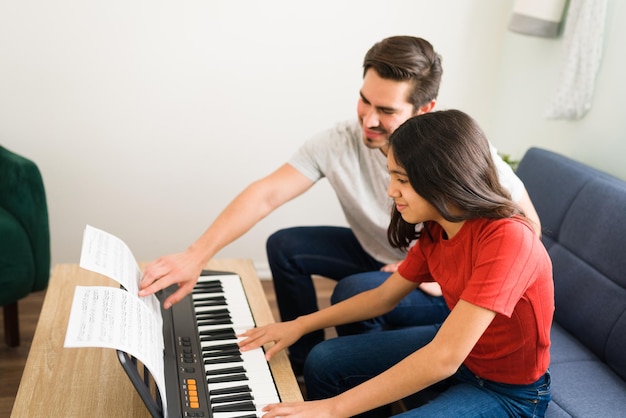 Desfrutando de uma ótima aula de piano em casa. Excelente e talentoso professor de música ensinando a uma menina pré-adolescente uma nova música no teclado