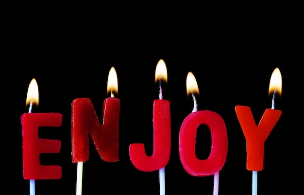 Foto desfrute de soletrado em velas de aniversário vermelhas contra um fundo preto