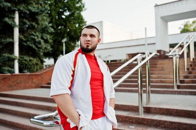 Desgaste de hombre musculoso barbudo joven en traje deportivo blanco con camisa roja