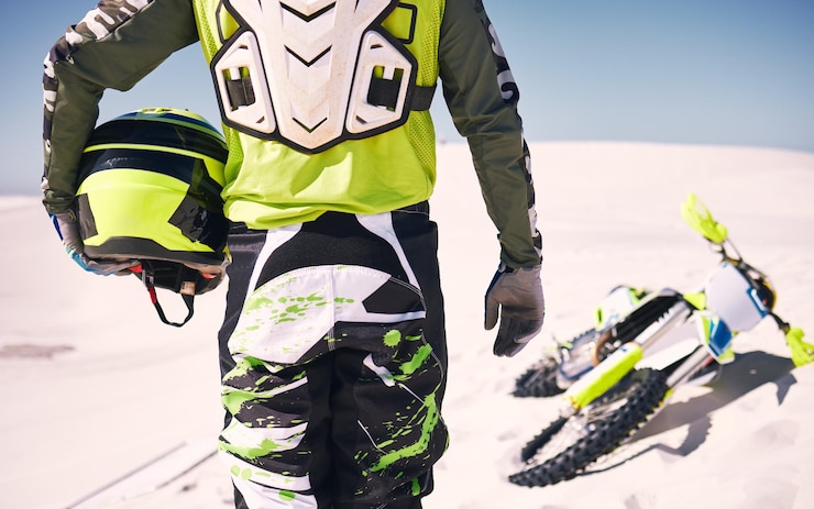 Foto desierto deportivo y espalda de una persona en motocicleta con casco para entrenamiento y desafío en arena viajes de transporte extremo y ciclista con motocicleta para aventura, libertad y adrenalina