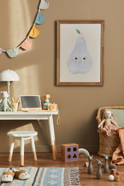 Design de interiores do elegante espaço infantil com mesa branca, laptop de madeira, brinquedos, acessórios infantis, lâmpada, decoração aconchegante e bandeiras de algodão penduradas na parede bege. quadro, armação.