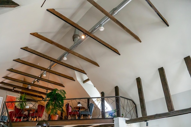 Design de interiores em um café Vista do teto no restaurante Tetos de designer vigas de madeira decorativas candelabros e lâmpadas de metal Tubo de ventilação ao longo do teto
