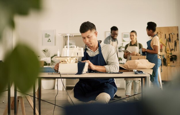 Design de moda e estilo com um jovem designer trabalhando em uma startup em uma máquina de costura em uma oficina Designer ocupado e criativo criando novas roupas da moda e da moda em uma pequena empresa