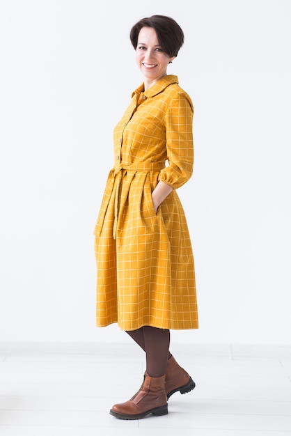 Design de roupas de pessoas com conceito de mulher atraente em um vestido amarelo posando em um quarto branco