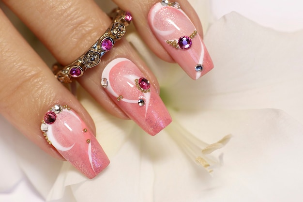 Design de unhas elegante com strass em um revestimento de esmalte rosa e branco na mão de uma mulher