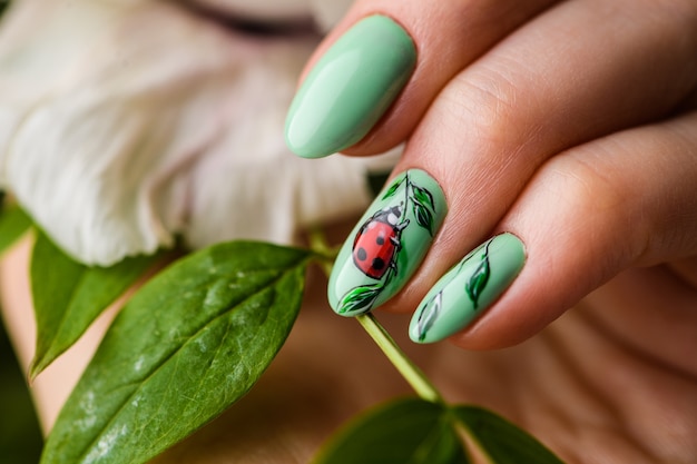 Design de unhas. Mãos com manicure verde brilhante com flores. Feche De Mãos Femininas. Art Nail.