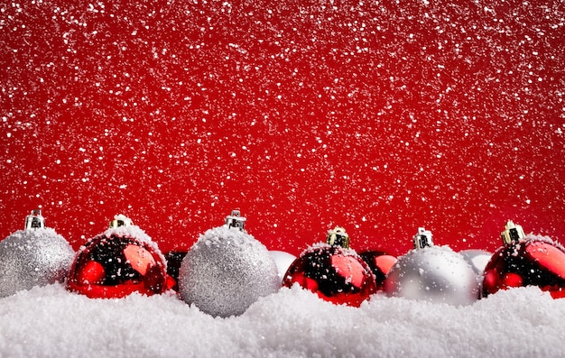 Design e plano de fundo do cartão de Natal. Enfeites vermelhos e prateados na neve em um pano de fundo vermelho, copie o espaço