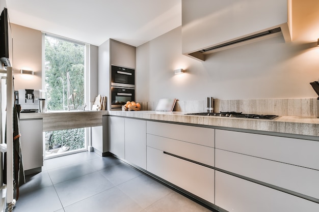 Design interior contemporâneo de cozinha em plano aberto com balcão de pedra em armários cinza em estilo minimalista