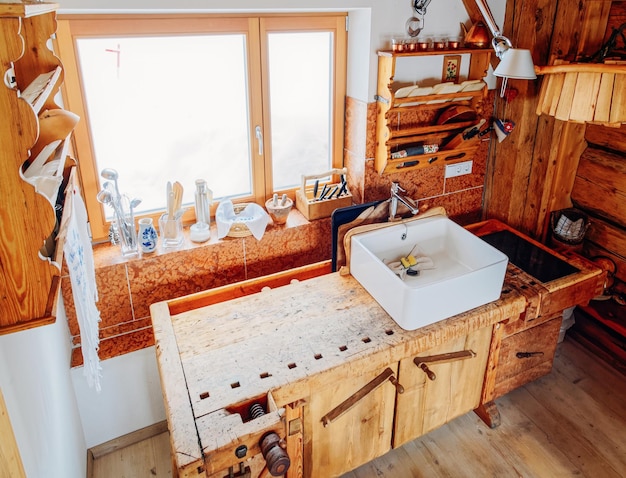 Design moderno do interior da cozinha em casa feito de materiais de madeira. Móveis de madeira em casa. Sala de jantar. Afundar. Cor marrom. Janela e utensílios de cozinha no fundo. Rústico contemporâneo e vintage feito à mão