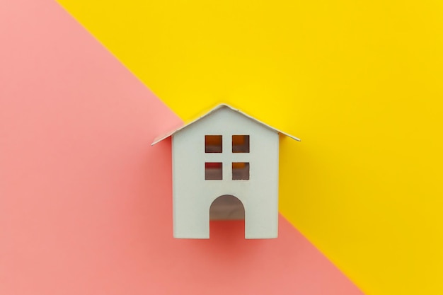 Foto design simplesmente minimalista com casa de brinquedo em miniatura branca isolada em amarelo e rosa colorido moderno mo ...