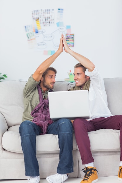 Designer arbeiten mit einem Laptop zusammen, dann hoch fiving