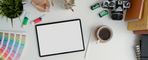 Designer-Arbeitstisch mit Mock-up-Tablet, Stift, Kamera, Büchern und Malwerkzeugen