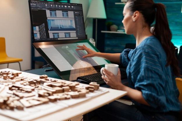 Designer arquitetônico fazendo esboço de engenharia usando computador de monitor de tecnologia de tela touchpad no local de trabalho de design. mulher caucasiana trabalhando no plano de construção para projeto de renovação