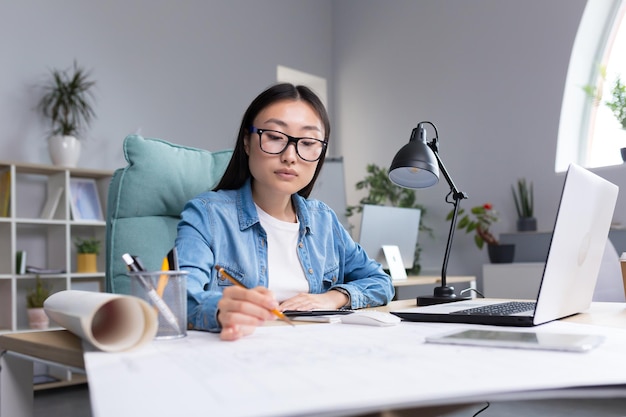 Designer asiático trabalhando no escritório com mulher de plantas no trabalho em roupas casuais