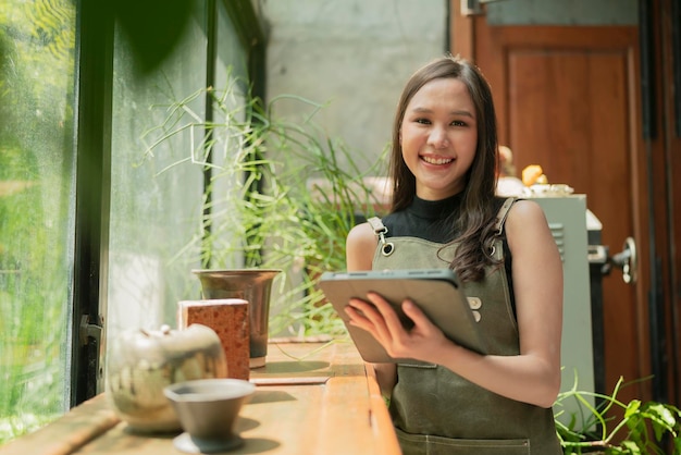 Designer criativo adulto feminino asiático felicidade pensando trabalho e pesquisa e anote ideias interessantes via tablet mulher asiática trabalhando casual relax em seu estúdio em casa com jardim de janela